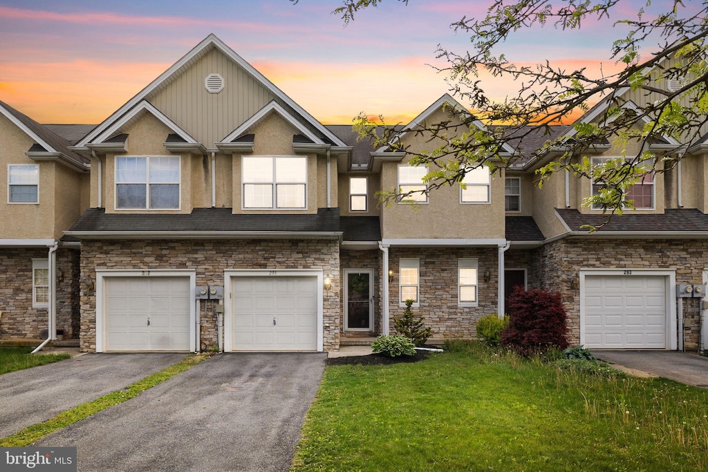 view of property with driveway, stucco siding, and stone siding