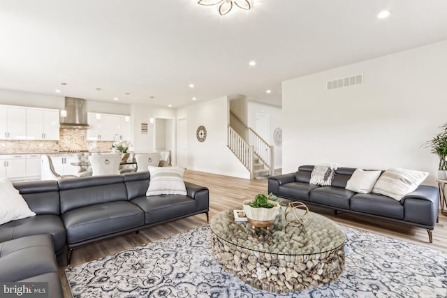 living room featuring stairs, light wood finished floors, and recessed lighting