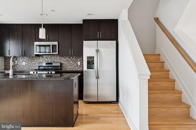 315 Dupont St, Philadelphia, PA 19128 - kitchen with stainless steel appliances, backsplash, dark stone counters, light wood-type flooring, and pendant lighting