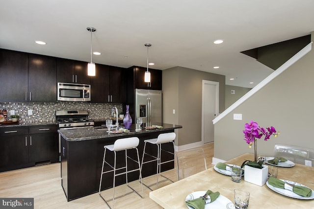315 Dupont St, Philadelphia, PA 19128 - kitchen with appliances with stainless steel finishes, a kitchen bar, decorative backsplash, a kitchen island with sink, and hanging light fixtures