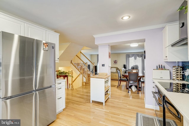 5941 Powells Landing Rd, Burke, VA 22015 - kitchen with freestanding refrigerator, light wood-type flooring, white cabinetry, wall chimney range hood, and ornamental molding