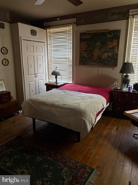 bedroom with hardwood / wood-style flooring, a ceiling fan, and a closet
