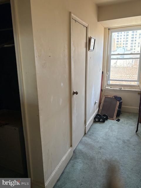 hallway featuring carpet flooring and baseboards