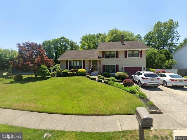 split level home featuring asphalt driveway, a garage, a front lawn, and a chimney