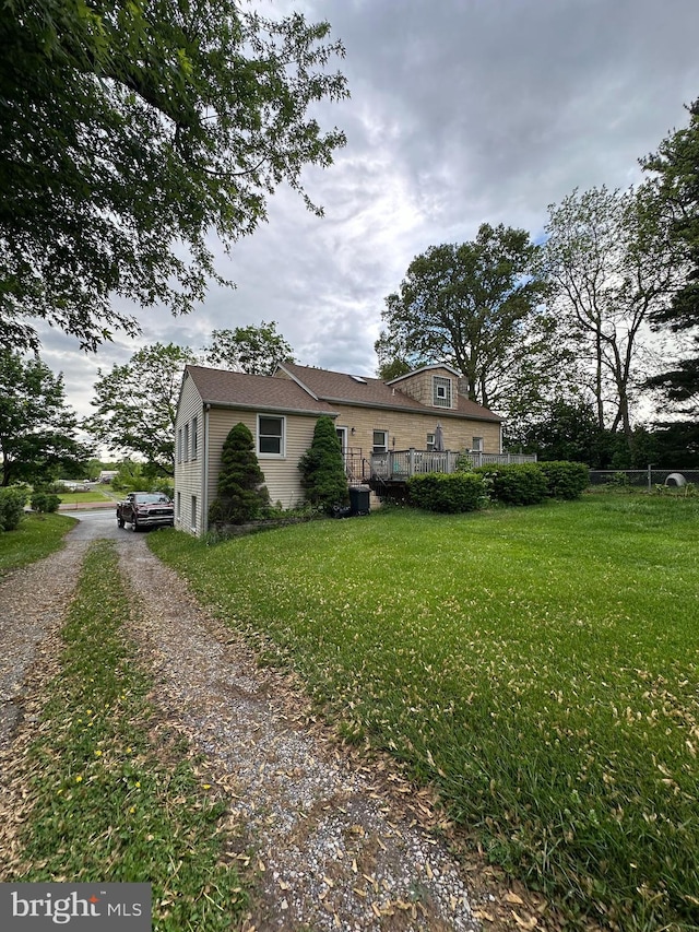 view of front of home featuring a front yard, a deck, and driveway