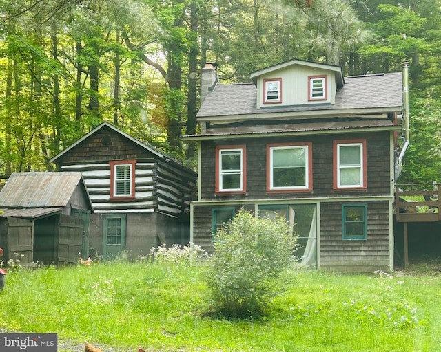 view of front facade with a chimney and roof with shingles