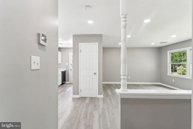 hallway featuring light wood finished floors, baseboards, and recessed lighting