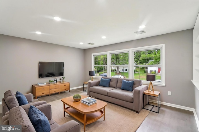 living room featuring baseboards, recessed lighting, and light wood finished floors