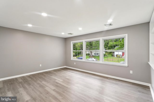 empty room featuring wood finished floors, baseboards, and recessed lighting