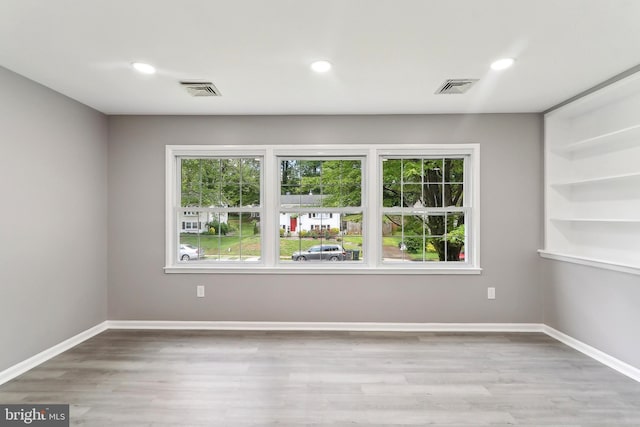 empty room with wood finished floors, baseboards, and recessed lighting