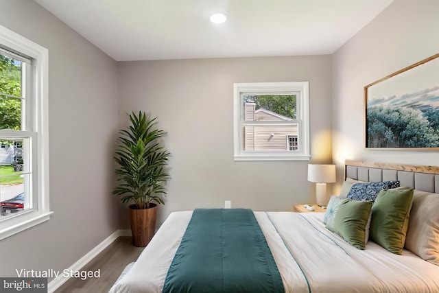 bedroom with multiple windows, wood finished floors, baseboards, and recessed lighting
