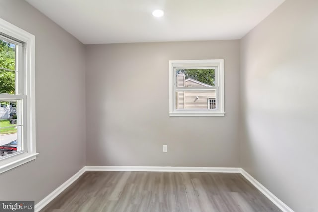 empty room featuring wood finished floors, healthy amount of natural light, baseboards, and recessed lighting