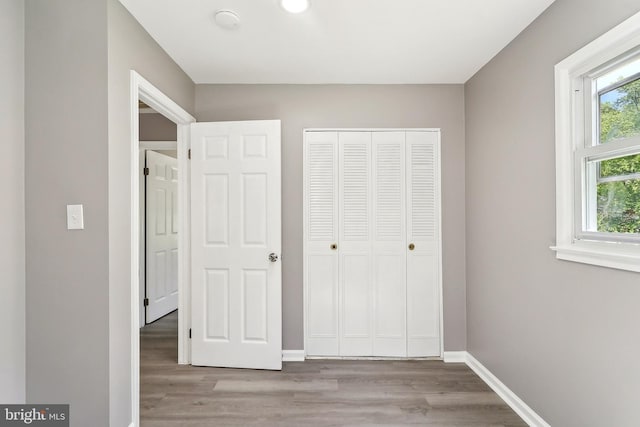 unfurnished bedroom with wood finished floors, multiple windows, and baseboards