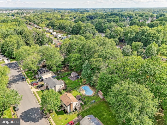 drone / aerial view of a heavily wooded area and a pool area