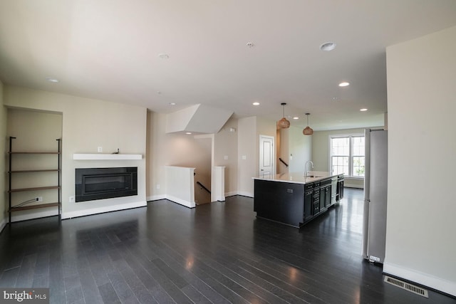 2519 Auden Dr, Silver Spring, MD 20906 - kitchen with freestanding refrigerator, light countertops, dark wood-style floors, an island with sink, and dark cabinets