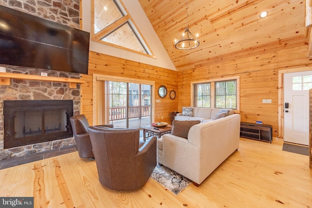 living room featuring plenty of natural light, wood finished floors, a fireplace, wooden walls, and a chandelier