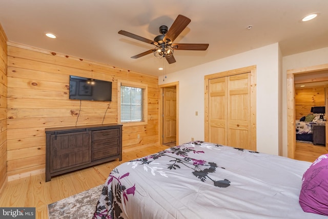 bedroom featuring light wood-style floors, wooden walls, recessed lighting, ceiling fan, and a closet