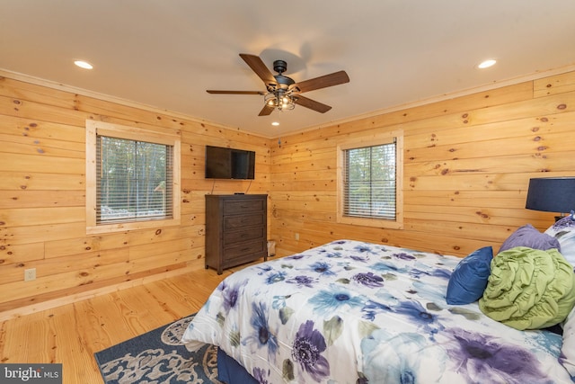 bedroom with wood finished floors, recessed lighting, wooden walls, ceiling fan, and ornamental molding