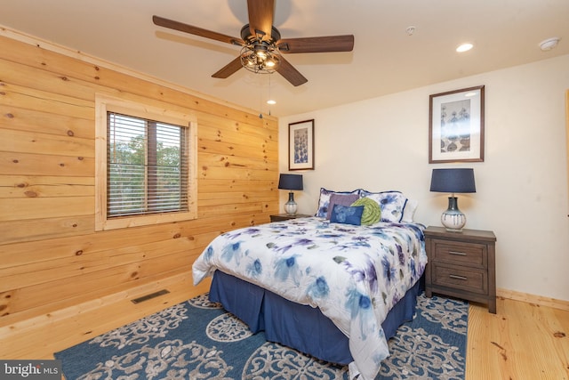 bedroom featuring wood finished floors, recessed lighting, baseboards, a ceiling fan, and wooden walls