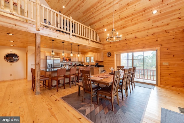 dining area with high vaulted ceiling, light wood finished floors, a chandelier, wooden walls, and recessed lighting