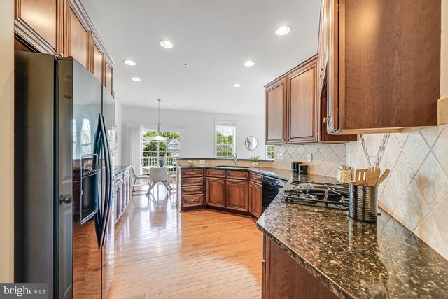 8217 Castanea Ln, Derwood, MD 20855 - kitchen with black appliances, a sink, light wood finished floors, a peninsula, and backsplash