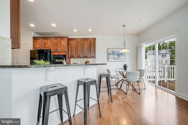 8217 Castanea Ln, Derwood, MD 20855 - kitchen featuring black appliances, a kitchen bar, brown cabinets, decorative backsplash, and recessed lighting