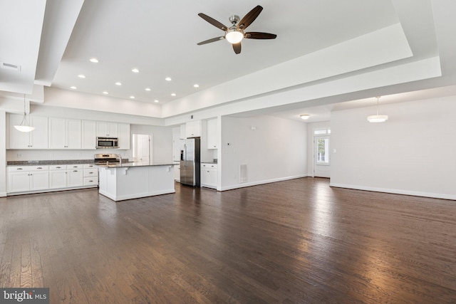 32157 Shorebreak Xing, Millville, DE 19967 - unfurnished living room with ceiling fan, dark wood finished floors, baseboards, a tray ceiling, and recessed lighting