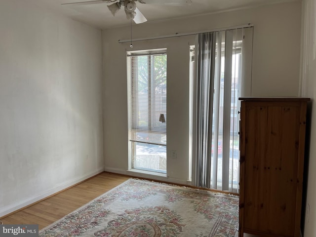 unfurnished room with ceiling fan, light wood-type flooring, and baseboards