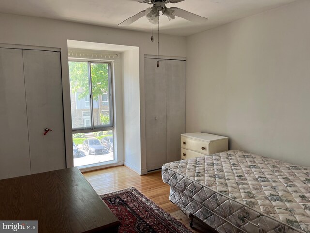 bedroom with light wood finished floors, two closets, and a ceiling fan