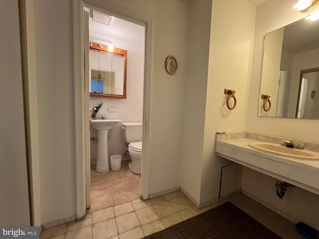 bathroom featuring a sink, tile patterned flooring, toilet, and baseboards