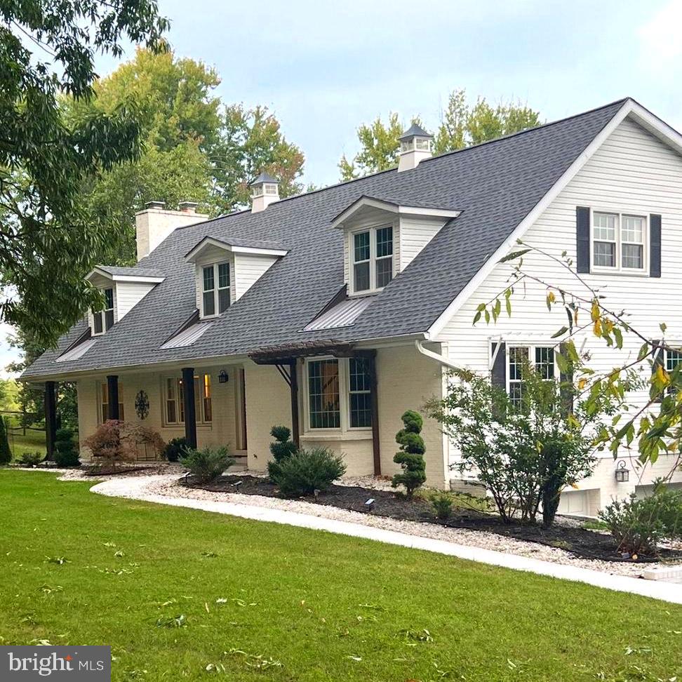 view of front of property with a chimney, a front lawn, roof with shingles, and covered porch