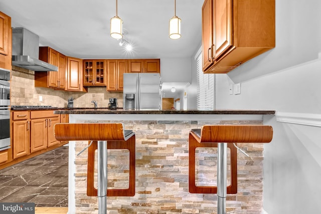 kitchen with wall chimney range hood, stainless steel fridge with ice dispenser, decorative backsplash, glass insert cabinets, and dark marble finish floors