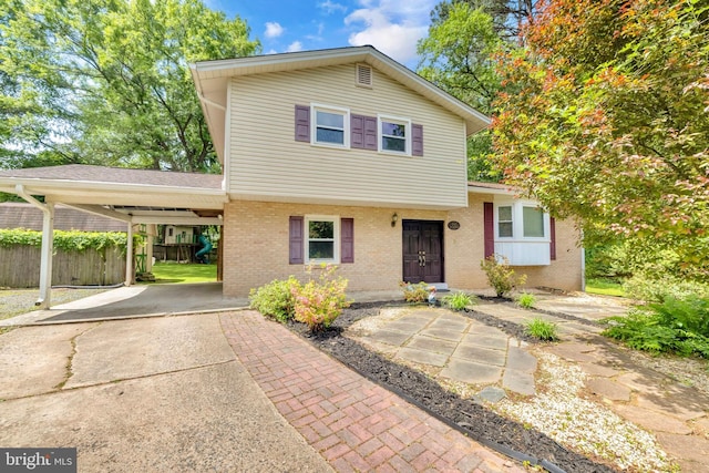 view of front of property with brick siding, fence, driveway, and an attached carport