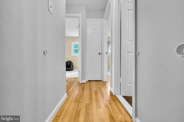 hall with light wood-type flooring and baseboards