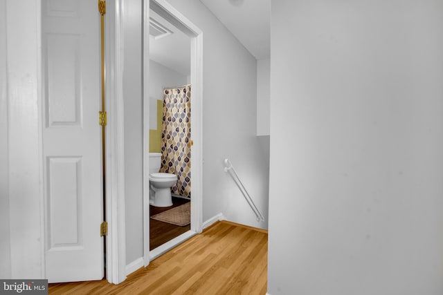 hall with an upstairs landing, light wood finished floors, and baseboards