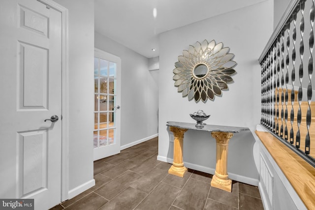 hall with baseboards and dark tile patterned flooring
