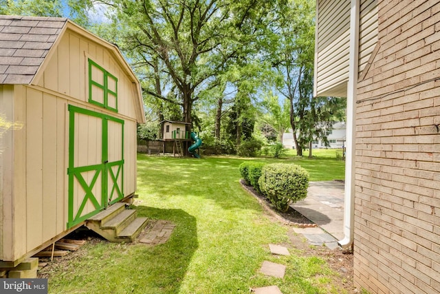 view of green lawn featuring a storage unit and an outbuilding