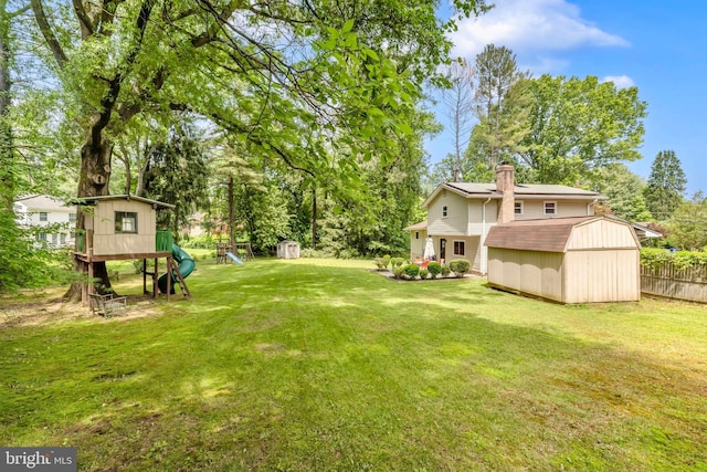 view of yard featuring a shed, an outdoor structure, a playground, and view of scattered trees