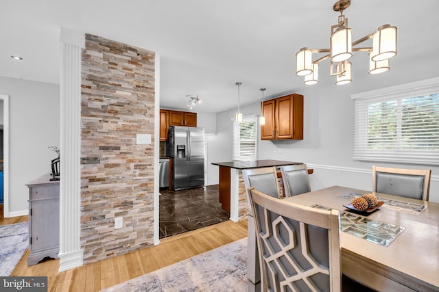 dining area featuring healthy amount of natural light, wood finished floors, and a chandelier