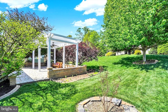 view of grassy yard with a ceiling fan, a pergola, and a patio area