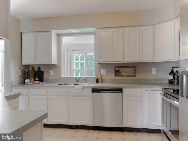 kitchen with appliances with stainless steel finishes, a sink, white cabinetry, and light countertops