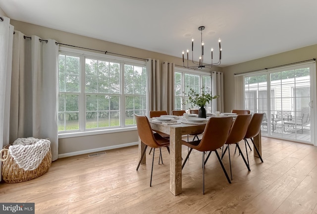dining space with a chandelier, light wood-type flooring, and baseboards