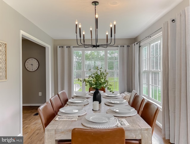dining area with a chandelier, wood finished floors, and baseboards