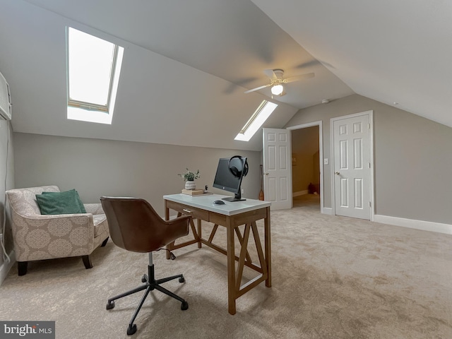 office area with a skylight, vaulted ceiling, light carpet, a ceiling fan, and baseboards