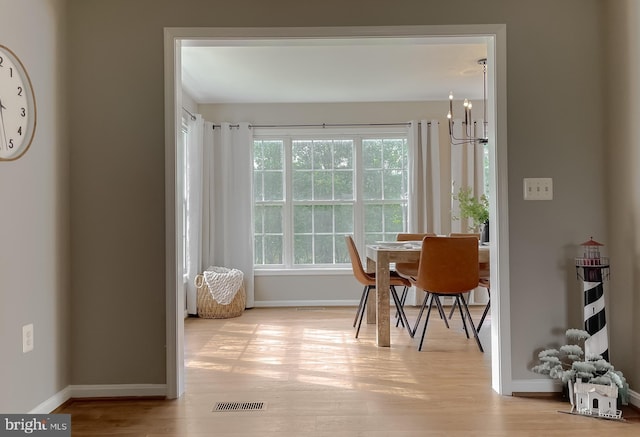 dining area with baseboards, wood finished floors, and a chandelier
