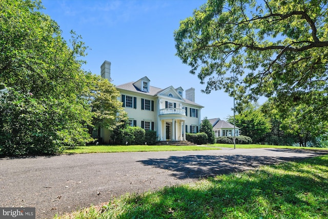 6437 Blantyre, Warrenton, VA 20187 - view of front of house with a balcony, a chimney, and a front yard