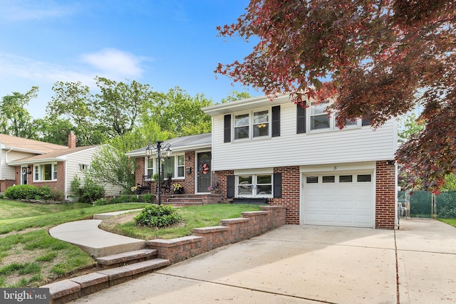 tri-level home with an attached garage, concrete driveway, a front yard, and brick siding