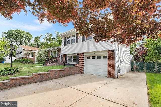 split level home featuring concrete driveway, a garage, and brick siding