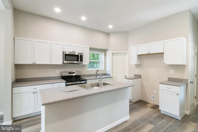 407 Lingle St, Osceola Mills, PA 16666 - kitchen with stainless steel appliances, white cabinetry, a center island with sink, light wood-style flooring, and recessed lighting