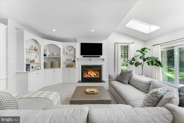 living area featuring a skylight, a fireplace with flush hearth, lofted ceiling, built in features, and recessed lighting